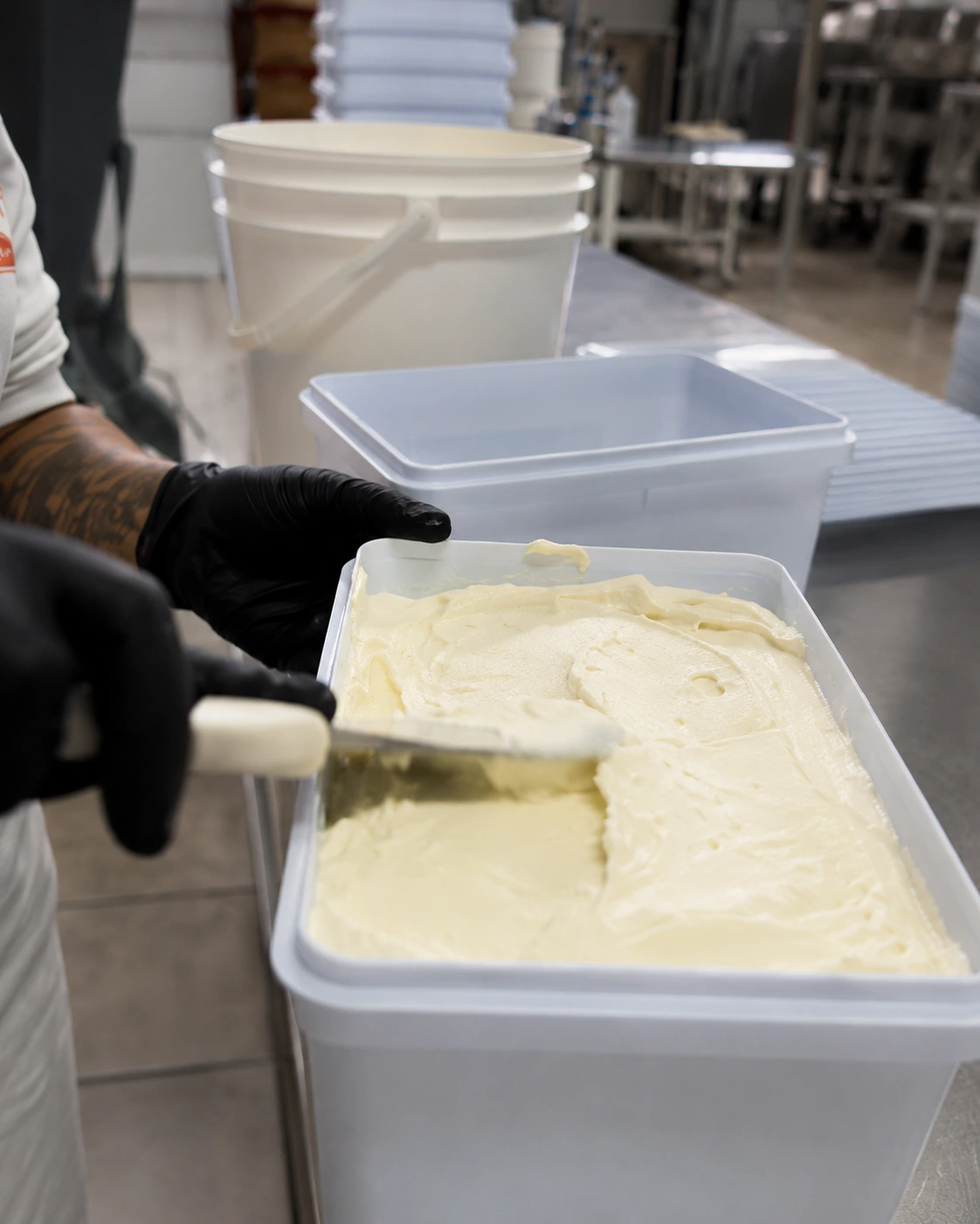 Profissional manipulando creme de sobremesa durante a produção da Particolare