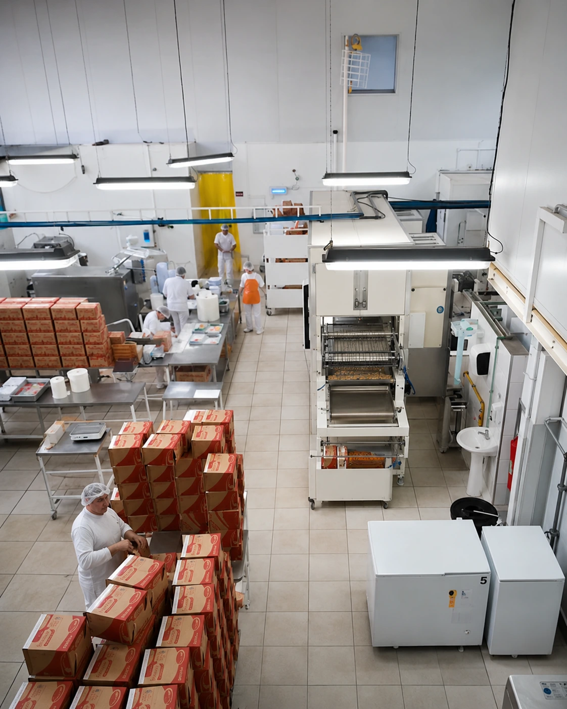 Área de produção da fábrica Particolare com equipe, equipamentos e caixas de produtos